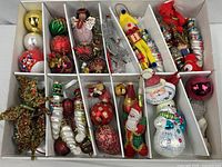 Overview of compartmentalized box with assorted ornaments in multiple materials and shapes