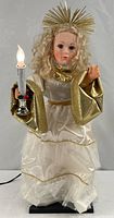 Front view of angel doll holding lighted candle