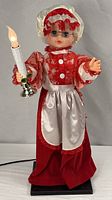 Front view of animated grandma doll holding lighted candle