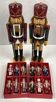 front view of two large nutcrackers and two trays of 12 mini ornaments