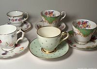 Five demitasse cup and saucer sets displayed
