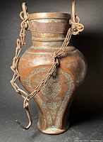 Full view of engraved brass vessel with attached iron chain and hook