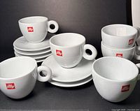 Front view of six Illy espresso cups stacked on six saucers
