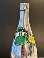 Upper section of silver Perrier bottle showing label and cap