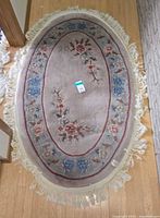 Full view of oval floral rug showing size, pattern and fringe