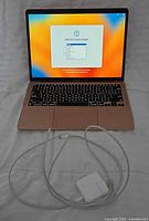 Laptop open, screen on setup page with charger and cable