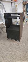 Front view of AV cabinet showing glass front door and casters