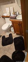 Overall bathroom view showing rugs, trash can, packaged chair covers, hand towels