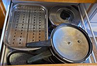 Drawer view showing roasting pan with rack, two pressure cookers and other cookware