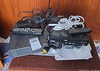 Stacked view of three media devices with remotes and cables