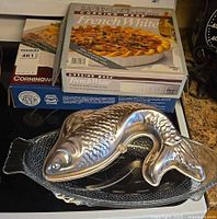 Overall lot showing casserole box, pie plate box, aluminum fish mold, glass fish platter