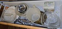 Drawer view showing glass bakeware, plastic mixing bowl, utensils and Progressive grater box