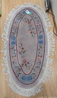 Full view of oval rug showing pattern, fringe and size tag