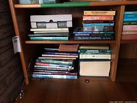 Shelf with mixed hardcovers and paperbacks, shows overall lot and Webster’s Dictionary