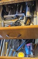 Open upper and lower kitchen drawers showing flatware tray and assorted utensils