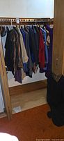 Row of hanging garments on closet rod showing jackets, blazers, cardigans and sweaters