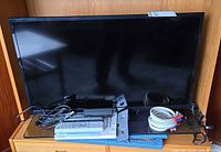 Front view of Samsung TV on stand with adapter, cable, remotes and manual