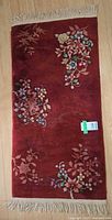 Full view of burgundy floral runner showing overall design and fringe
