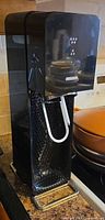 Front view of black SodaStream Source soda maker showing drip tray and tube