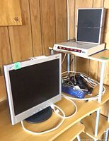 Monitor, surge suppressor on shelf below, basket of cables