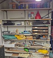 Full view of pegboard shelving with mixed tools, gloves, funnels, hardware organizer, tarps