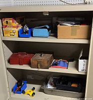 Cabinet shelves with boxed DuraHook kits, metal and wooden toolboxes, plastic trays, cardboard box of hardware