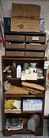 Full shelving unit showing box of sanding discs on top, drawer organizer with hardware, rope, cord, toolbox