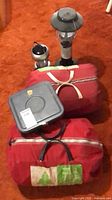 Overall lot showing two red sleeping robe bags, two lanterns, square container