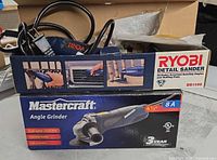 Ryobi DS1100 detail sander box atop Mastercraft 4-1⁄2" 8A angle grinder box; partial view of tools and cords