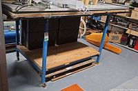 Full view showing top surface, blue steel frame, casters, and lower shelf