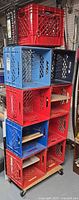 Stack of red, blue and black plastic milk crates on wood dolly
