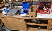 overview of lot on workbench showing sink basin, tool case, blue trays, red crate