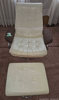 Front view of cream vinyl lounge chair and ottoman showing upholstery, tufting, arm pads, chrome bases