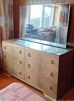 Front view of dresser with attached mirror showing nine drawers, glass top and brass pulls