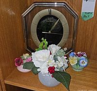 Octagonal Daniel Dakota wall clock, grey pot with silk flowers, two porcelain flower baskets displayed on shelf
