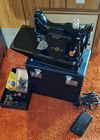 Singer sewing machine on carry case with foot pedal and accessory tray visible