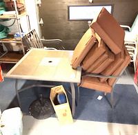 Square tile-top patio table with stacked cushioned chairs and decorative metal umbrella base