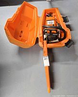 Chainsaw inside open orange carrying case with bar scabbard attached