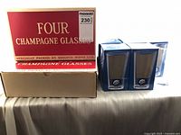 Box labeled Four Champagne Glasses by Brights Wines Ltd alongside two retail boxes of Mott's Clamato pint glasses