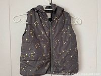 Front view of grey puffer vest with gold stars and hood