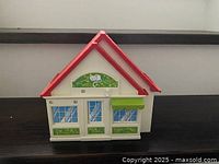 Front view of white and green Playmobil folding dollhouse with red roof
