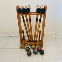 Full croquet set on wheeled stand showing mallets and stakes