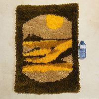 Full view of rectangular latch-hook rug beside water bottle for scale