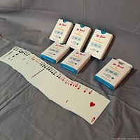 Six decks in tuck boxes with one deck opened showing full spread of cards