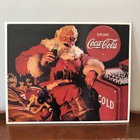 Front view of metal sign showing Santa with Coca-Cola bottle and cooler