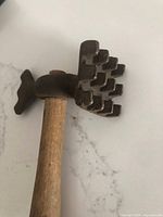 Close-up of toothed cast iron tenderizer head attached to wooden handle