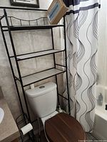 Black metal over-toilet shelf positioned above toilet