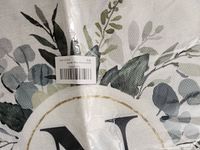 Close-up of garden flag’s N monogram and foliage design in packaging
