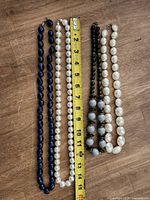 Four beaded necklaces laid beside tape measure for length reference