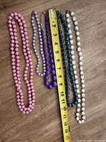 All five necklaces beside tape measure showing lengths